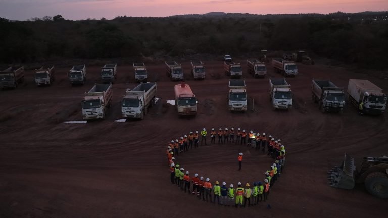 Flotte de camions alignés et équipes réunies sur un site à l'aube