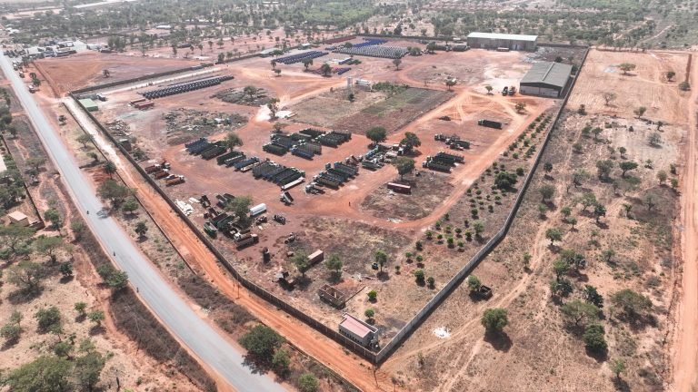 Parc d'équipements clôturé, engins et bâtiments, vue aérienne