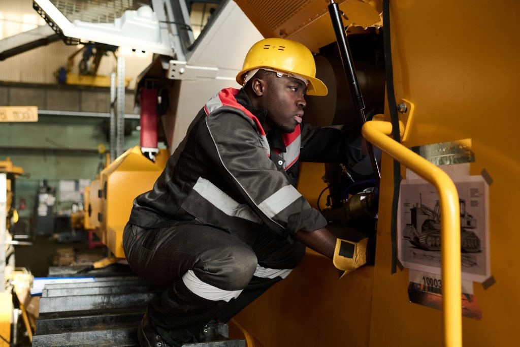 Technicien en casque de chantier vérifiant le mécanisme d'un engin lourd