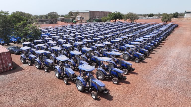 Tracteurs bleus neufs alignés en rangs serrés sur un parc